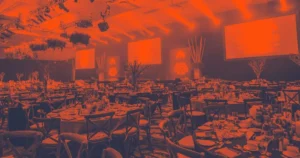 Deciding on a Gala Event Venue? Don't Make These 3 Mistakes a large gala event venue set up with tables, chairs, plates, silverware and decorations in front of a stage