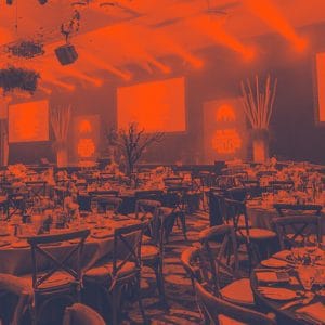 Deciding on a Gala Event Venue? Don't Make These 3 Mistakes a large gala event venue set up with tables, chairs, plates, silverware and decorations in front of a stage