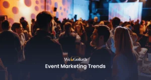 6 Event Marketing Trends to Elevate Your Events in 2025 A networking event with people gathered in a dimly lit room, highlighting a presentation slide titled "Event Marketing Trends.