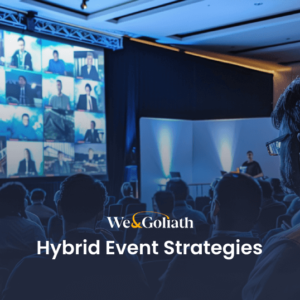 Audience at a hybrid event viewing multiple virtual speakers displayed on a large screen, with the text "webgoliath hybrid event strategies" overlaying the image.