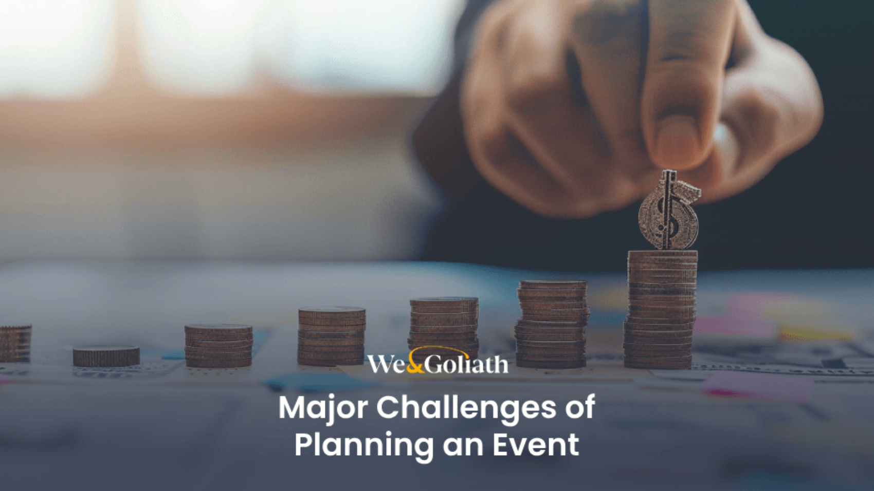 A hand stacks coins in ascending piles on a desk with the text "key challenges of planning an event" overlaid.