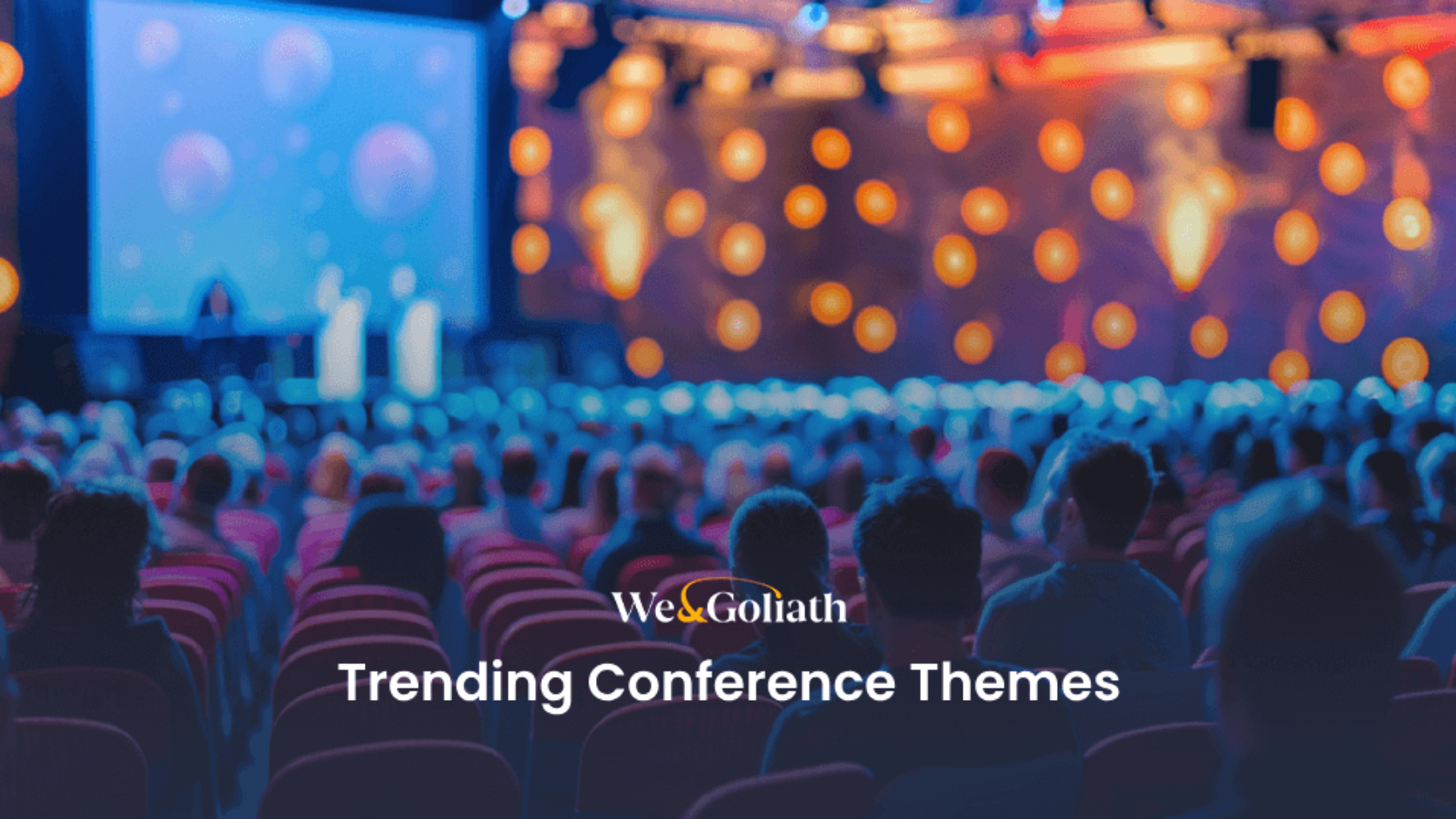 Audience at a conference with focus on the stage, lights dimmed, text overlay "trending conference themes" and logo "we&goliath.