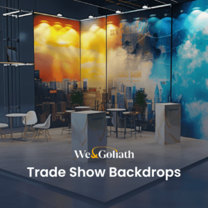 A modern exhibition booth with vibrant cityscape and cloud murals, featuring minimalist furniture including tables, chairs, and podiums, and two potted plants, set in an industrial hall.