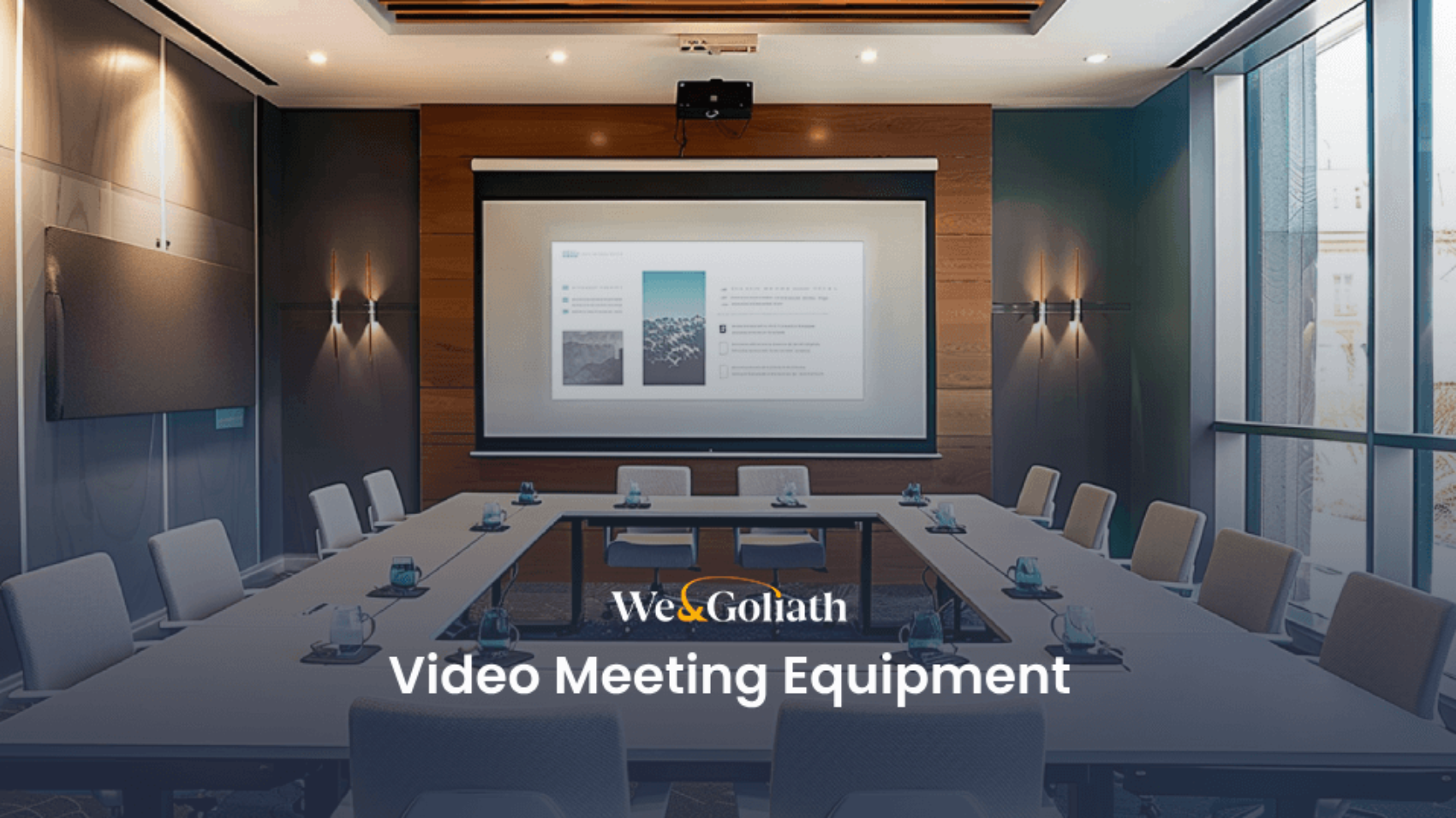 A modern conference room equipped with a large screen displaying a presentation, surrounded by tables and chairs set up for a video meeting. Text reads "We & Goliath Video Meeting Equipment.