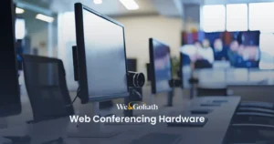 The Best Video Conferencing Hardware for Businesses A row of computer monitors equipped with webcams is shown in an office setting. The text reads "We&Goliath Web Conferencing Hardware.