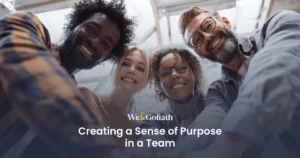 How to Create a Sense of Purpose in a Team We and Goliath cover for creating a sense of purpose in a team, showing colleagues looking down at camera