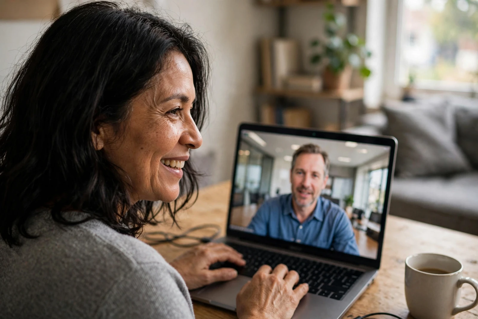 A remote attendee smiles during a video call with a colleague.